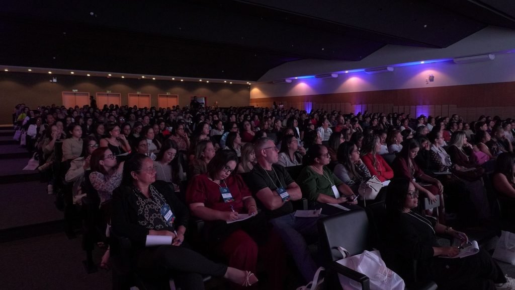 Auditório lotado durante o II Seminário Pernambucano de Autismo, com público sentado nas fileiras e iluminação azul e roxa nas paredes.